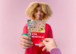 Photo d'une personne qui donne une prospectus avec marqué "être bénévole"